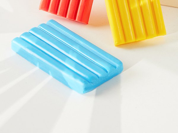 Close-up of colorful polymer clay bars on a white surface with soft shadows.
