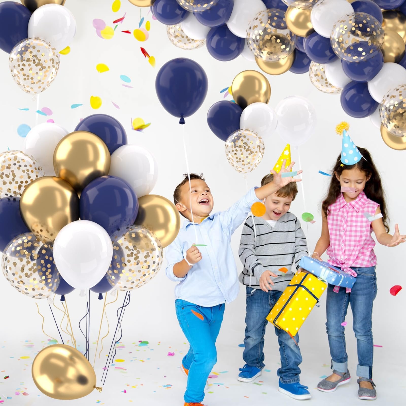 Three children celebrating with navy blue, gold, and white balloons and confetti.