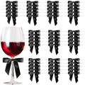 Black satin twist tie bows arranged in rows next to a wine glass filled with red liquid