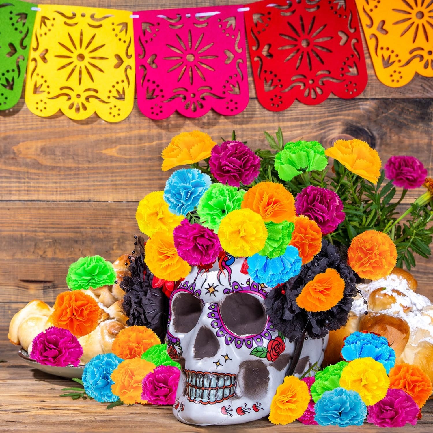 Day of the Dead altar setup with a decorated skull, pan de muerto, and colorful artificial marigold flowers.
