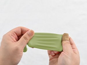 Hands stretching a sage green latex balloon against a white background