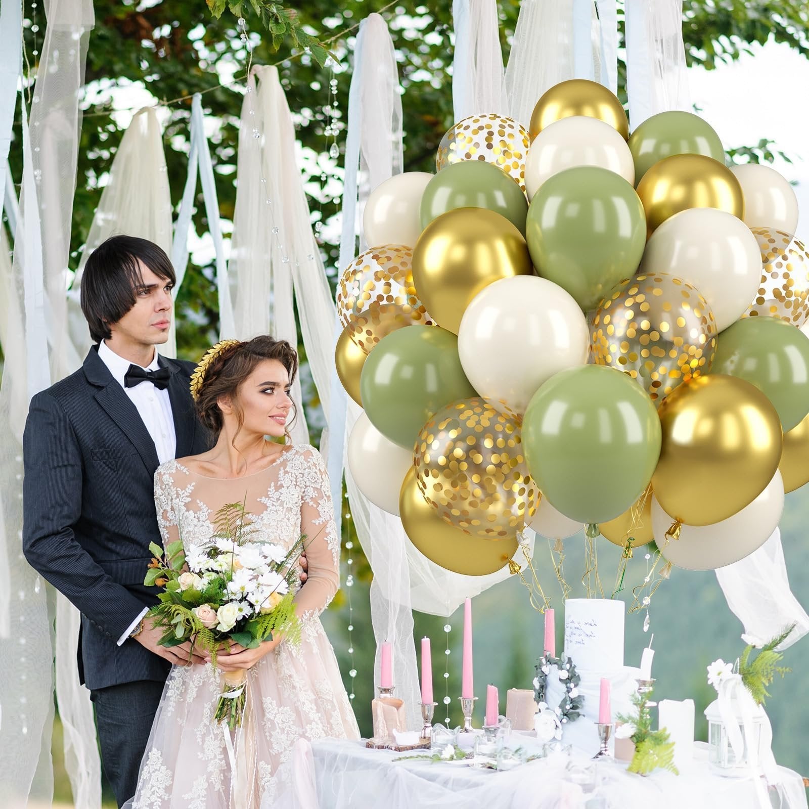 Bride and groom posing with a large bouquet of sage green, gold, and cream balloons at a wedding reception table.