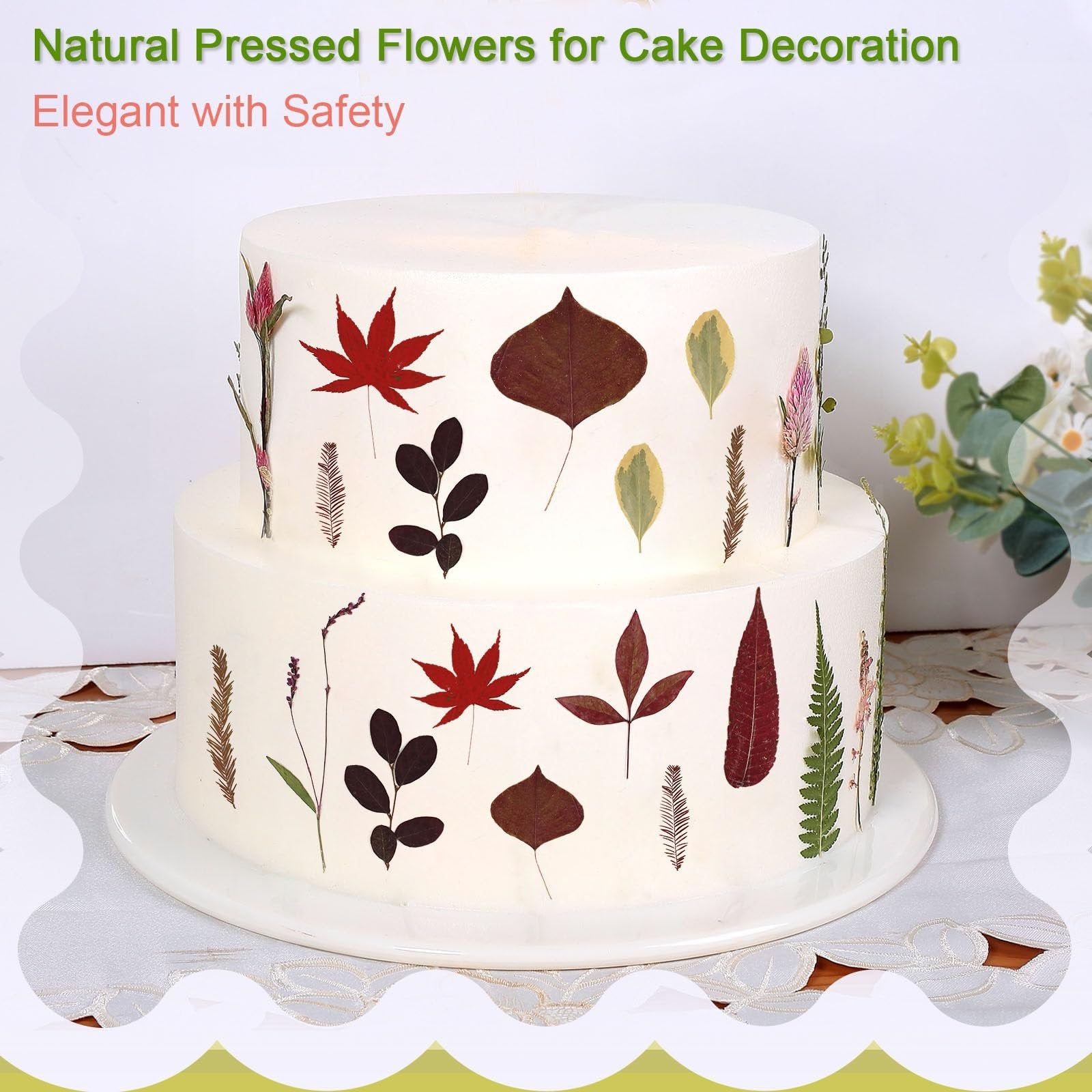 Two-tier white cake decorated with various dried pressed leaves and flowers in fall colors.