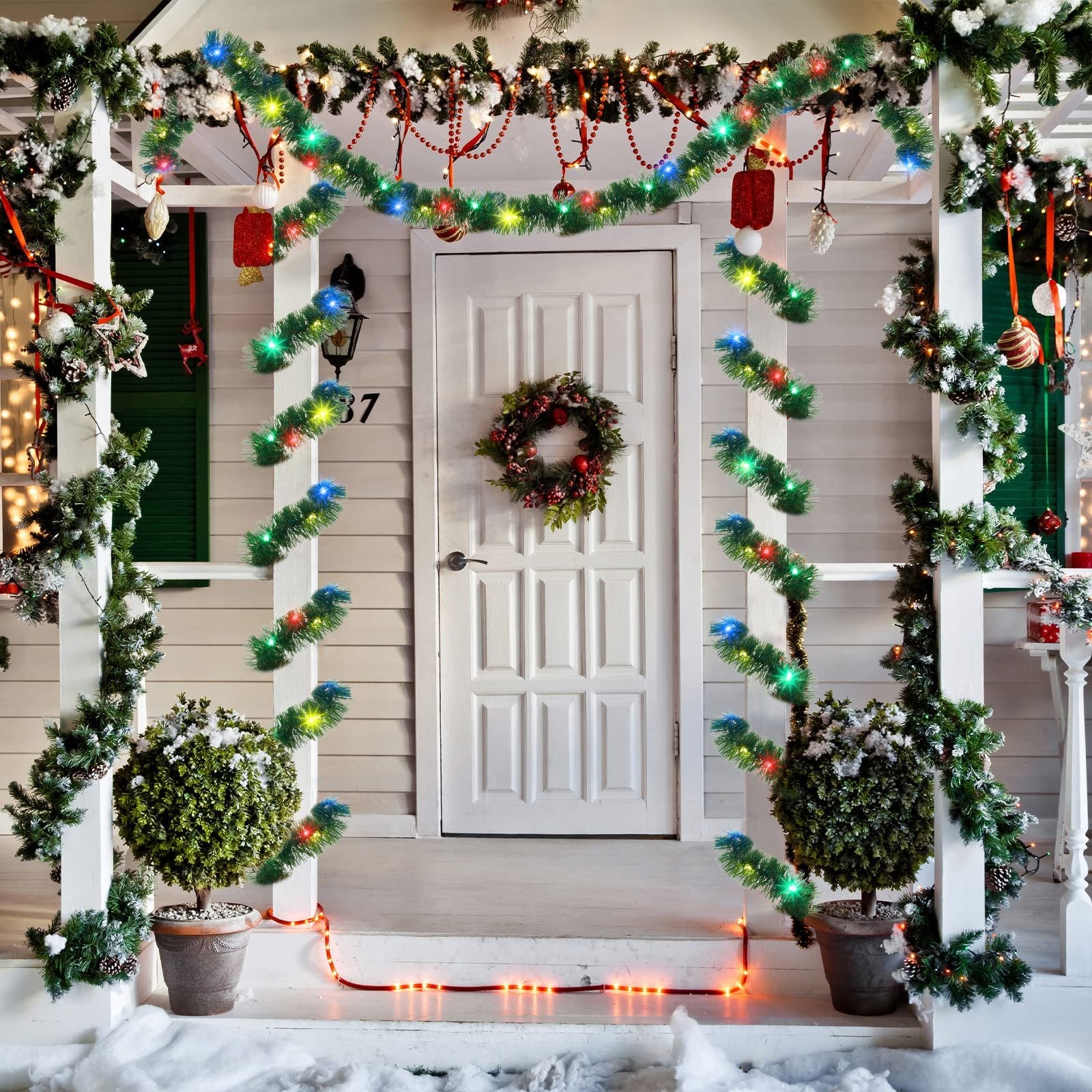 Christmas garland with colorful LED lights decorating a porch with a white door and wreath