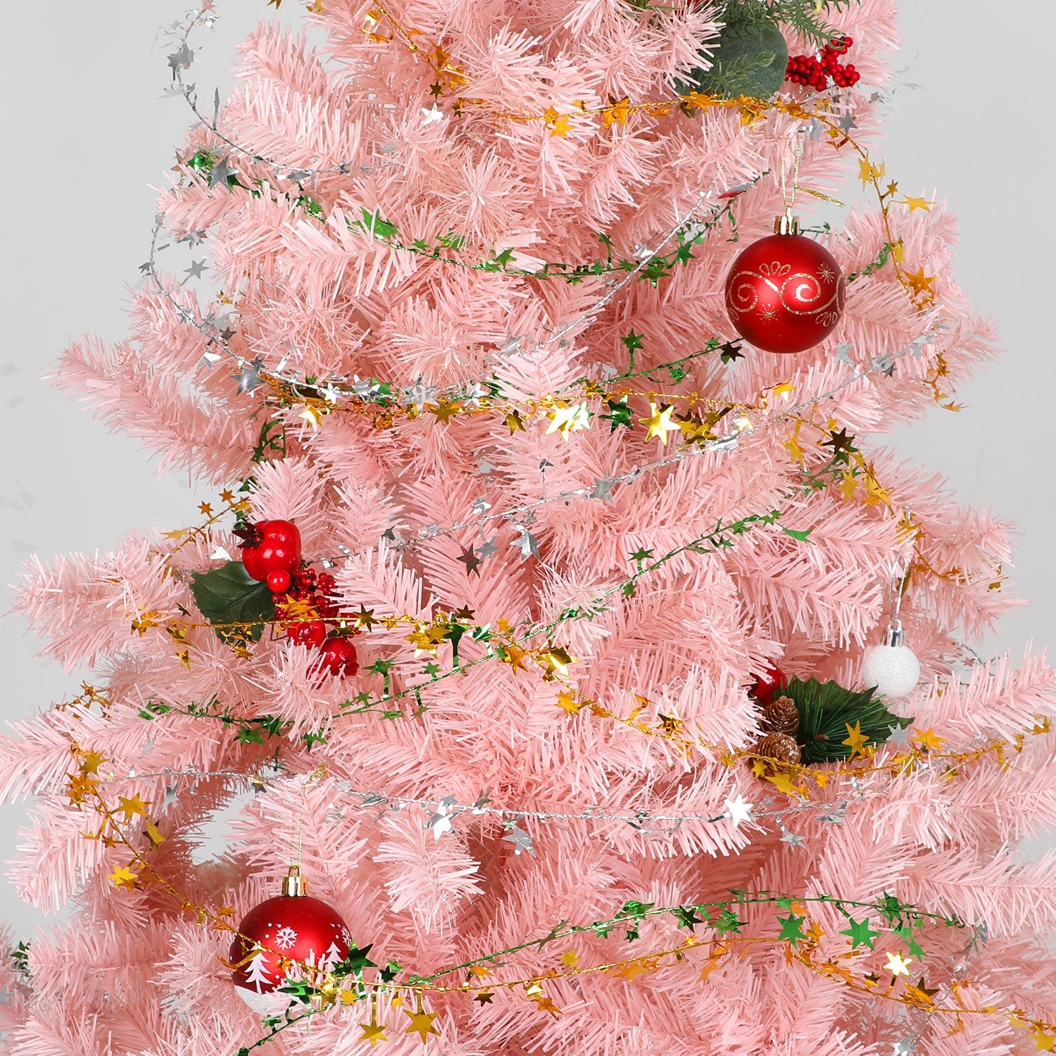 Pink Christmas tree decorated with gold and silver star tinsel garland and red ornaments.