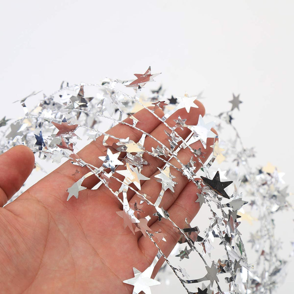 Hand holding a strand of silver star tinsel garland against a white background.