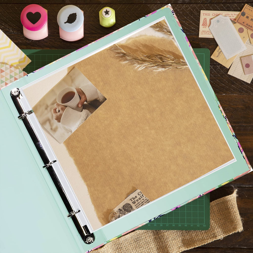 Open scrapbook binder with a photo of hands holding a mug of tea and decorative paper inside.