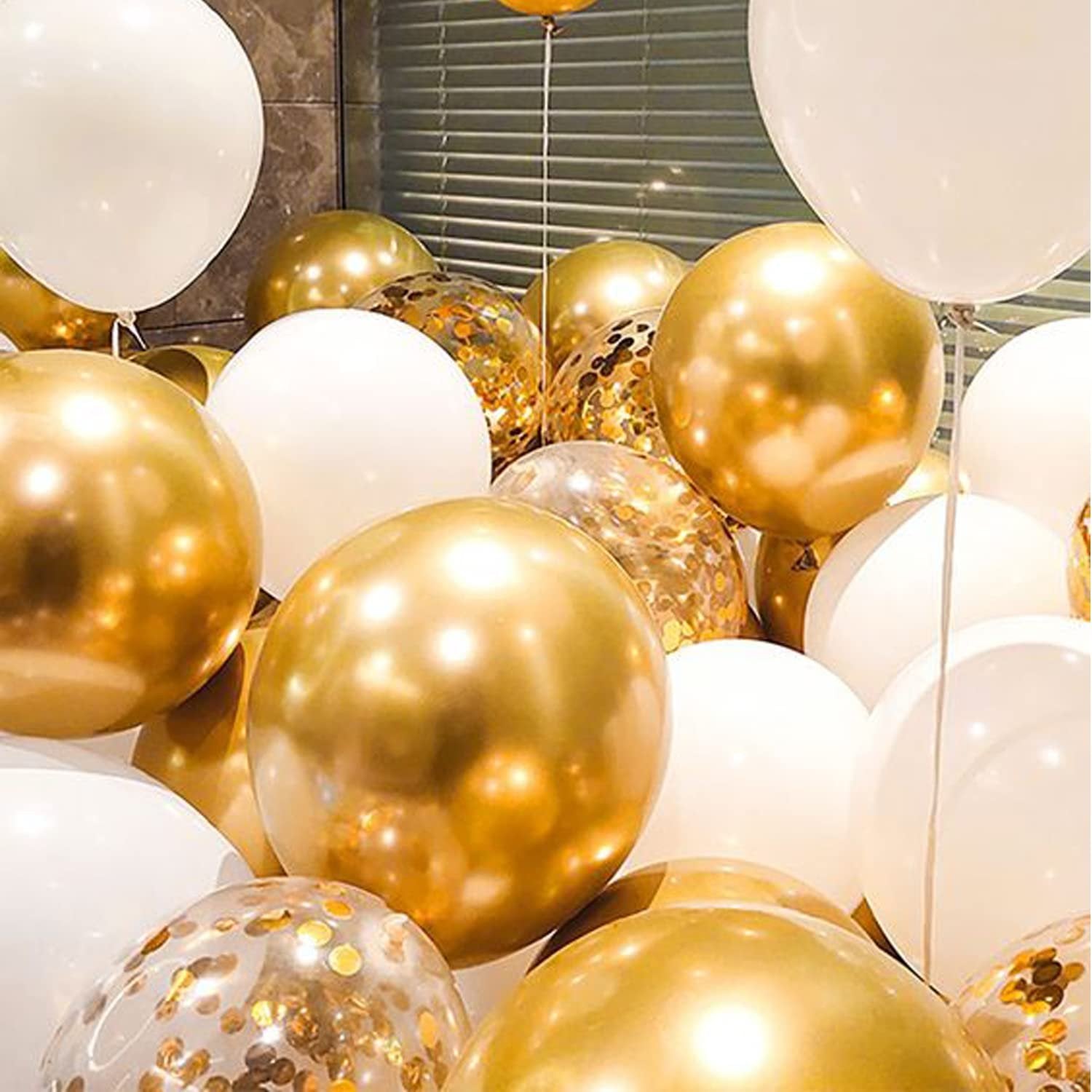Close-up of a large cluster of white and gold balloons, some filled with gold confetti.