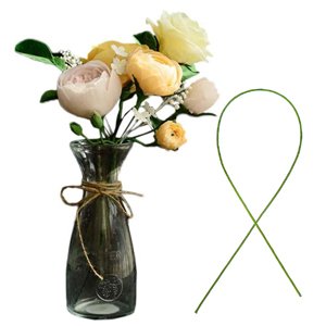 Dark green floral stem wire bent into a loop next to a glass vase with artificial flowers.