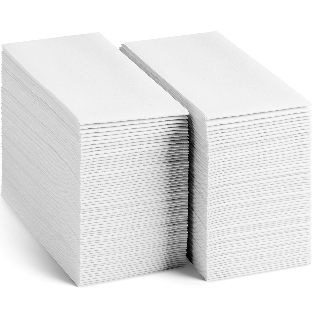 Two stacks of white disposable linen-feel guest towels on a white background, angled view.