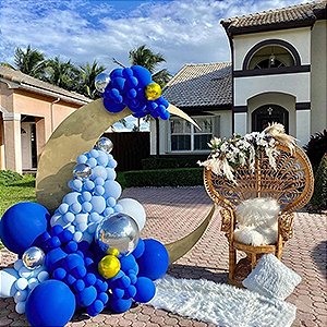 Balloon arch and crescent moon decoration with peacock chair and rug outside a house