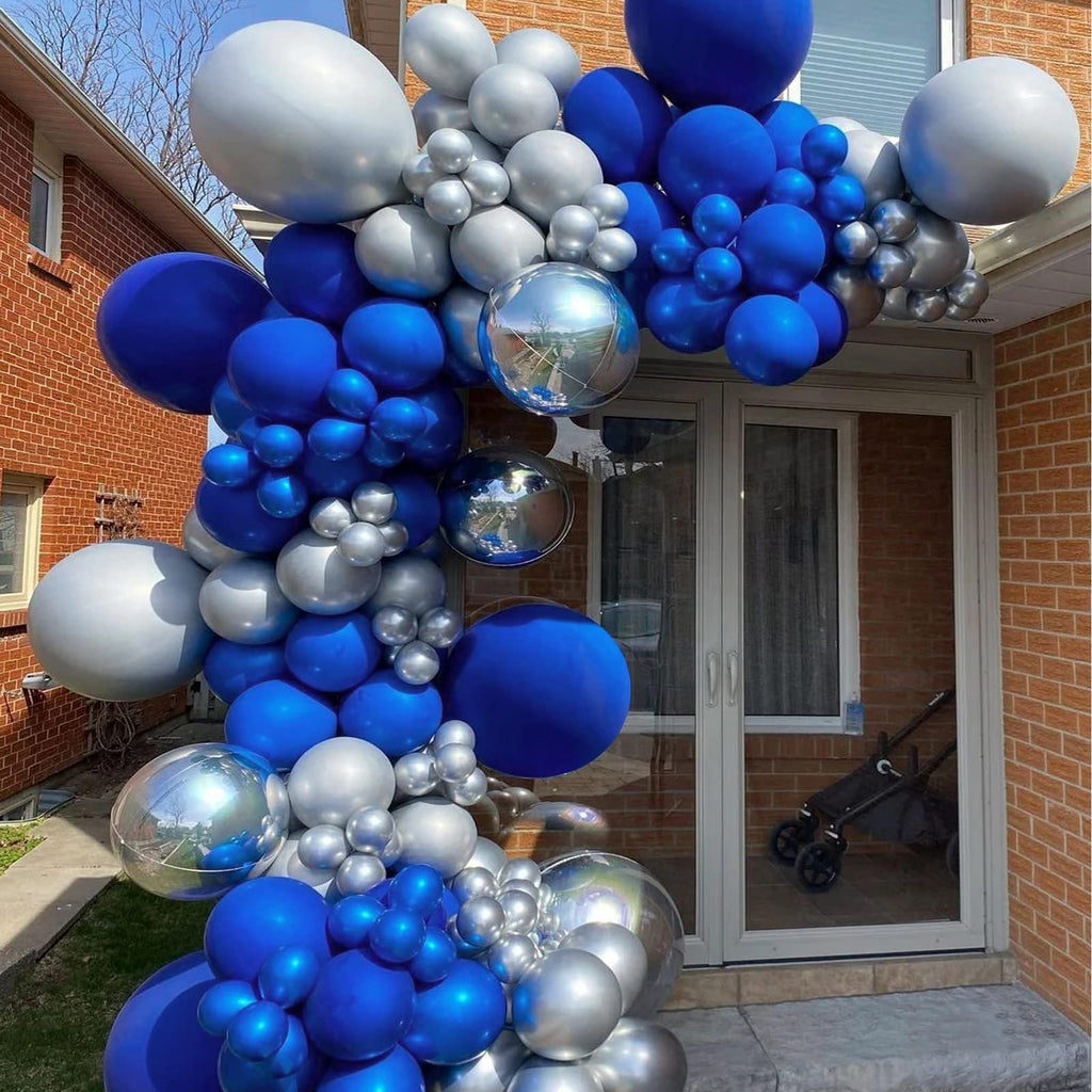Royal blue and silver balloon arch decoration on a brick house exterior with a double door.