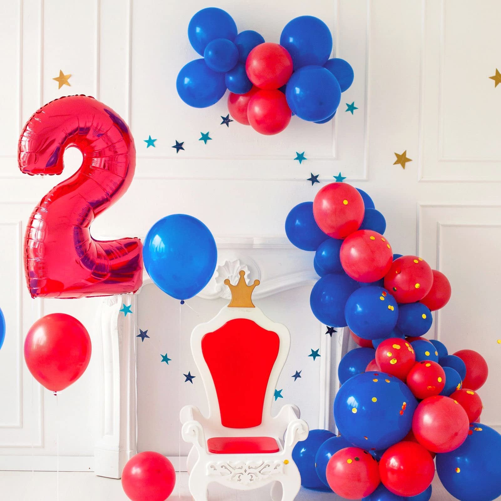 Red foil number 2 balloon and blue and red latex balloons arranged around a white throne with a gold crown.