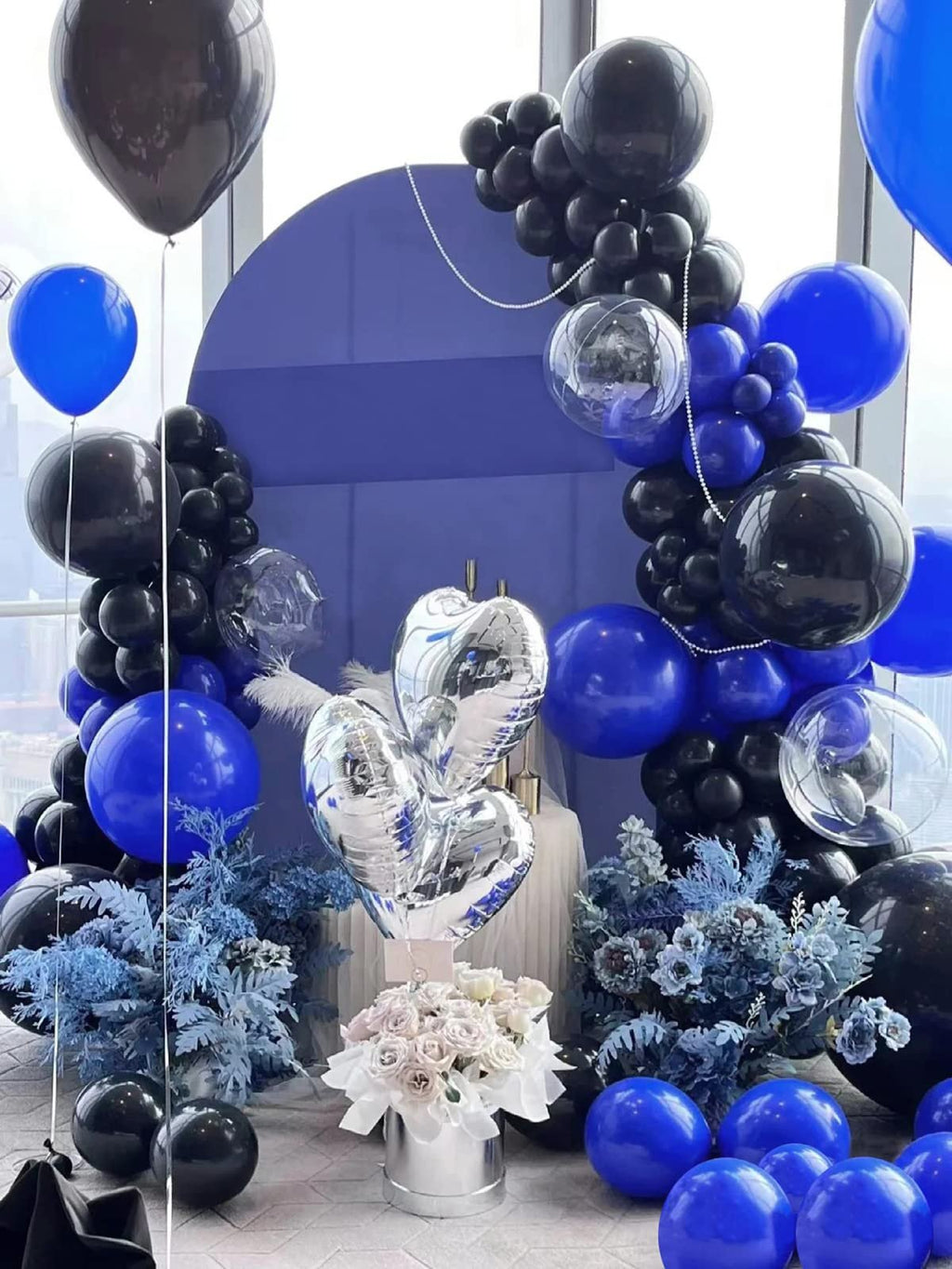 Balloon arch and arrangement in royal blue and black with silver heart balloons and white roses