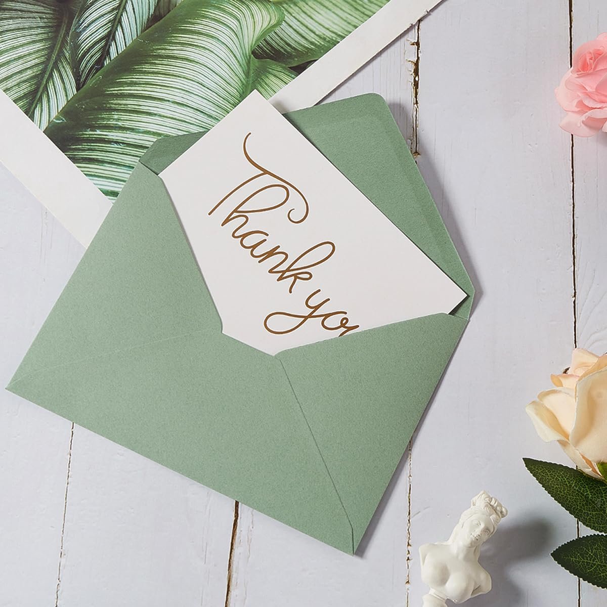 Sage green A7 envelope with a thank you card inside, surrounded by decorative elements.