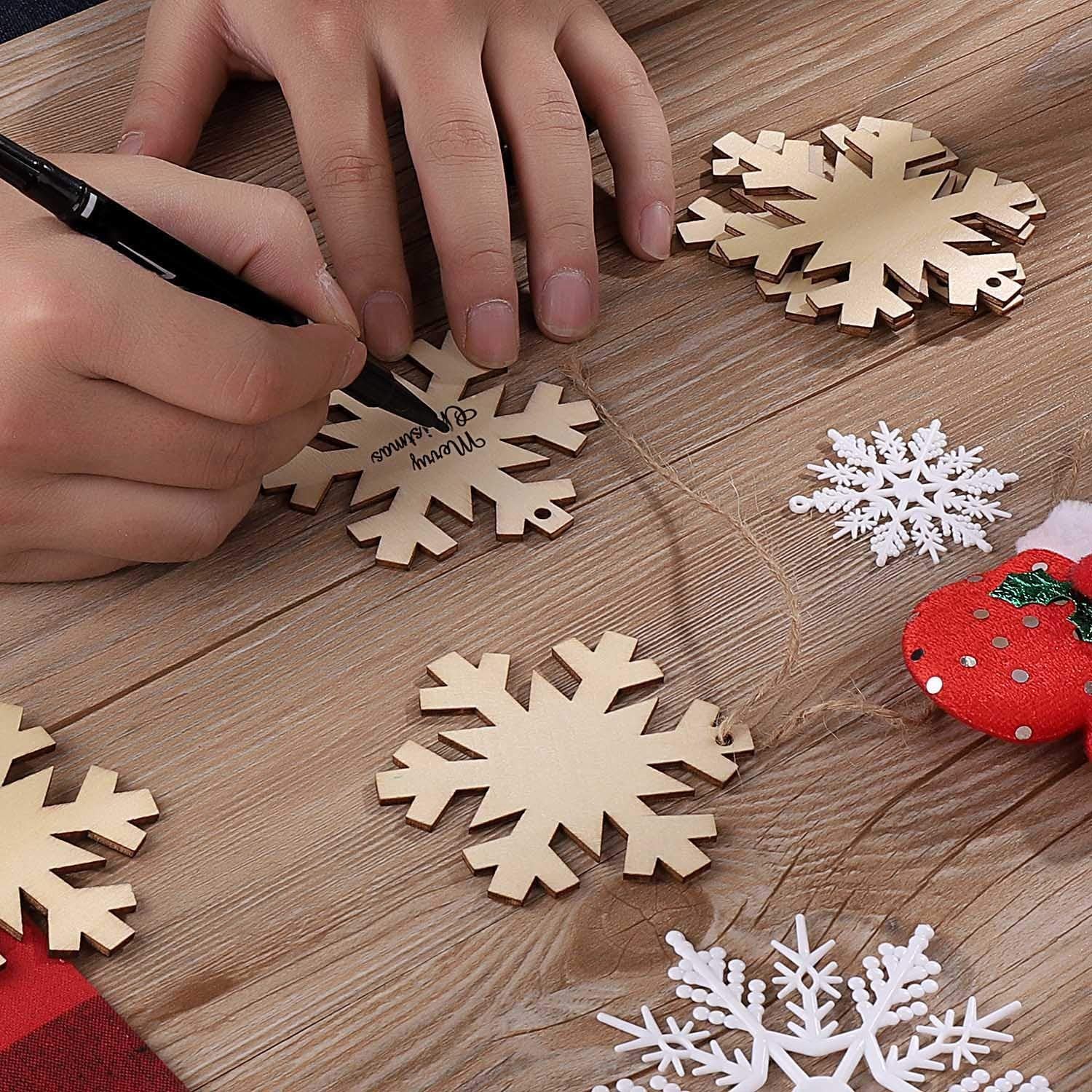 Hands writing Merry Christmas on unfinished wooden snowflake ornament with black marker