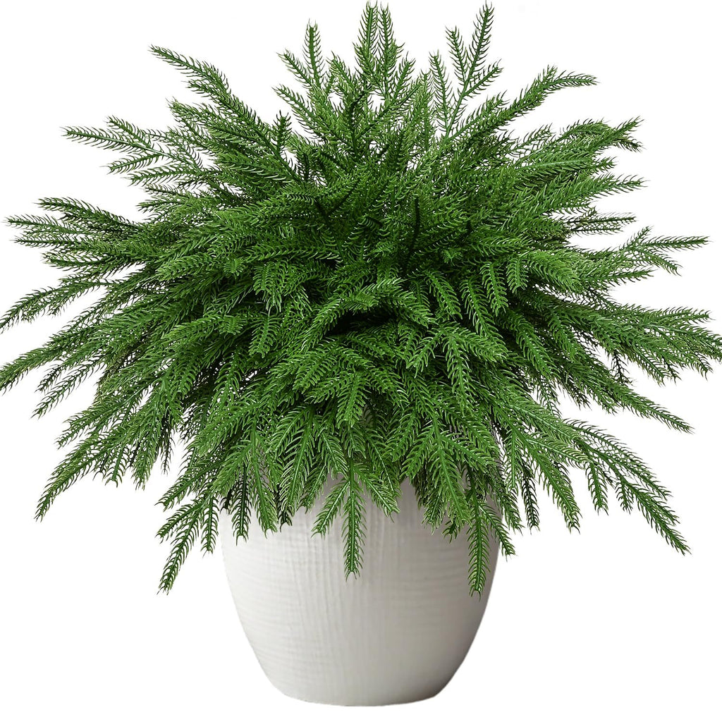 Artificial Norfolk pine stems in a white textured pot, isolated on white background.
