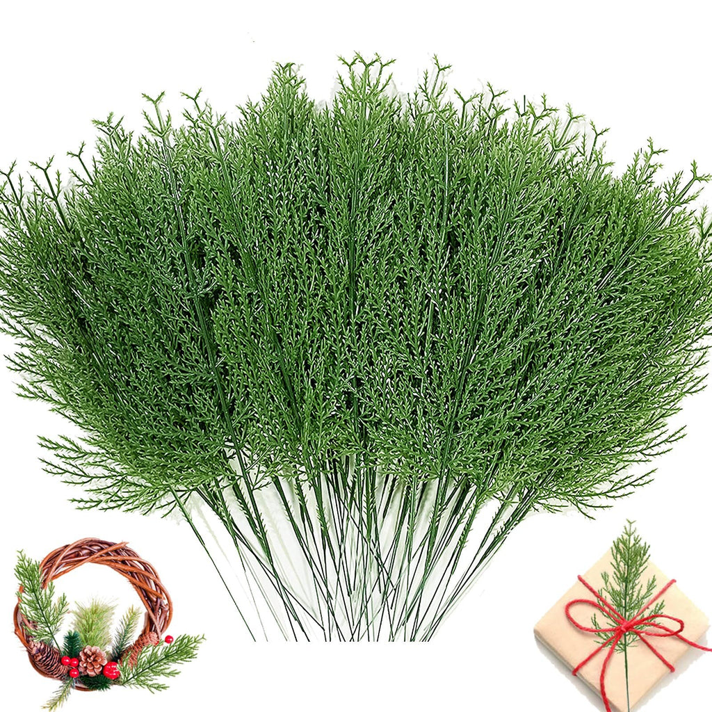 Bundle of artificial green pine branches with a small wreath and gift box in the lower corners