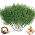 Bundle of artificial green pine branches with a small wreath and gift box in the lower corners