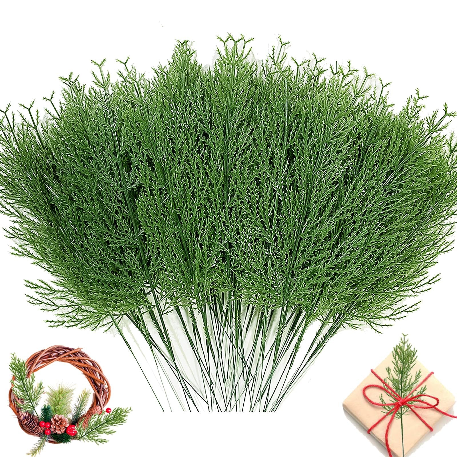 Bundle of artificial green pine branches with a small wreath and gift box in the lower corners