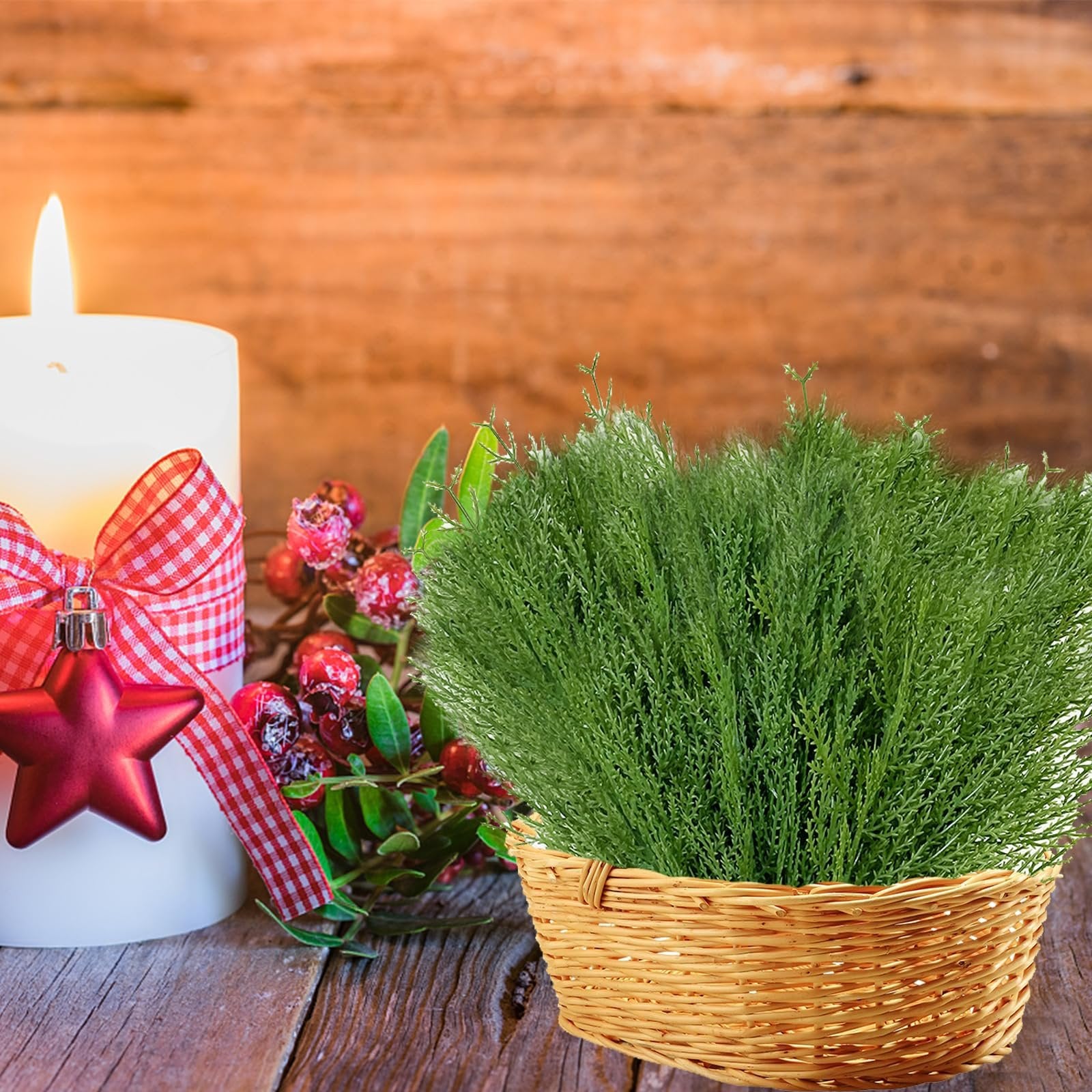 Artificial pine branches in a basket next to a lit candle with a red star ornament and berries