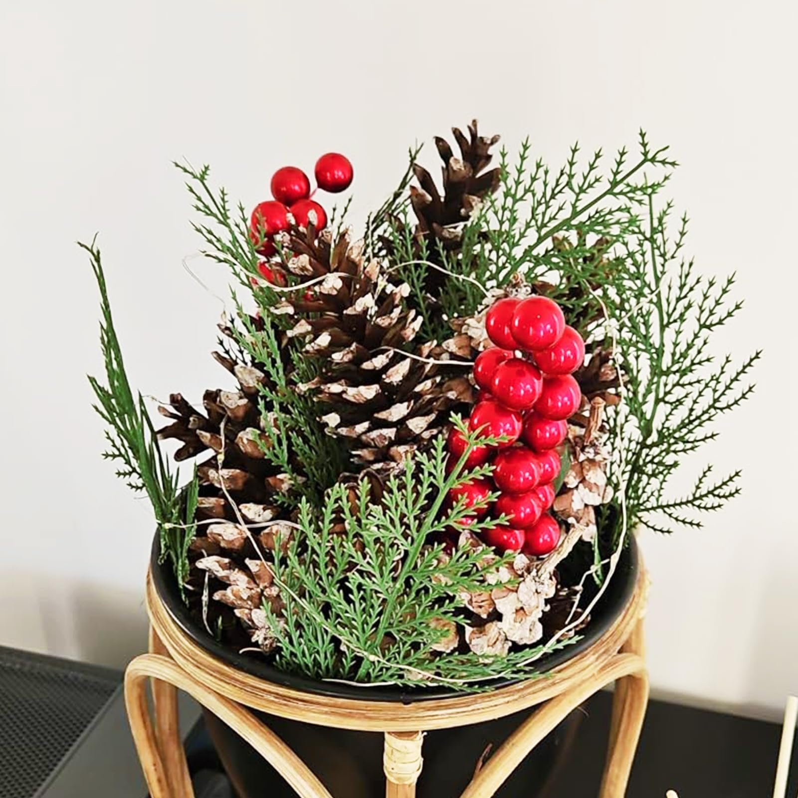 Artificial pine branches with pine cones and red berries in a decorative pot