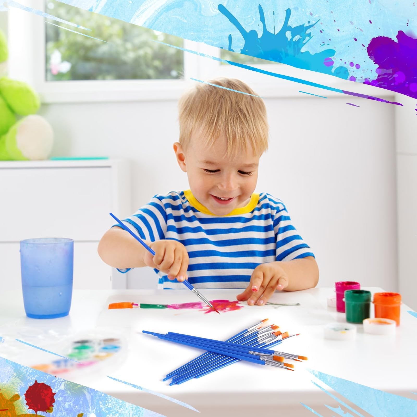 Young boy painting with blue handled brushes and colorful paints on white paper