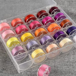 Transparent plastic storage case filled with colorful sewing machine bobbins, angled view.