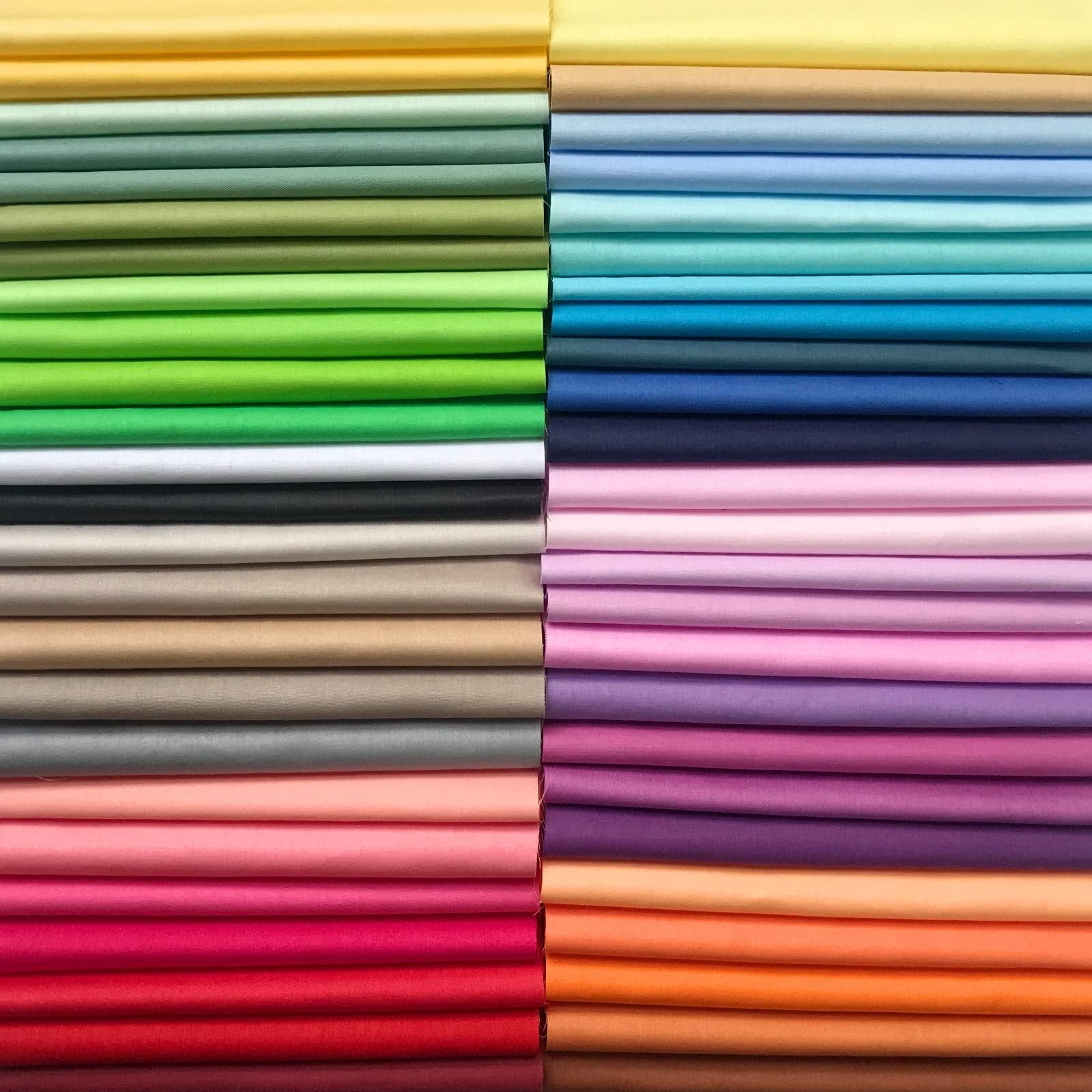 Stack of 100% cotton fabric squares in 50 solid colors, neatly folded in rows.