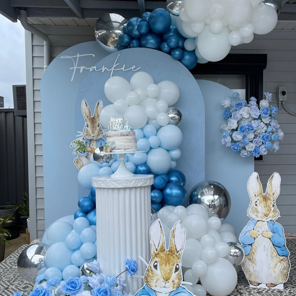 Birthday party setup with blue and white balloons, a cake, and Peter Rabbit cutouts.