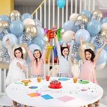Four children in party hats celebrating with dusty blue, gold, and confetti balloons around a table.