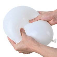 Hands squeezing a white latex balloon against a white background
