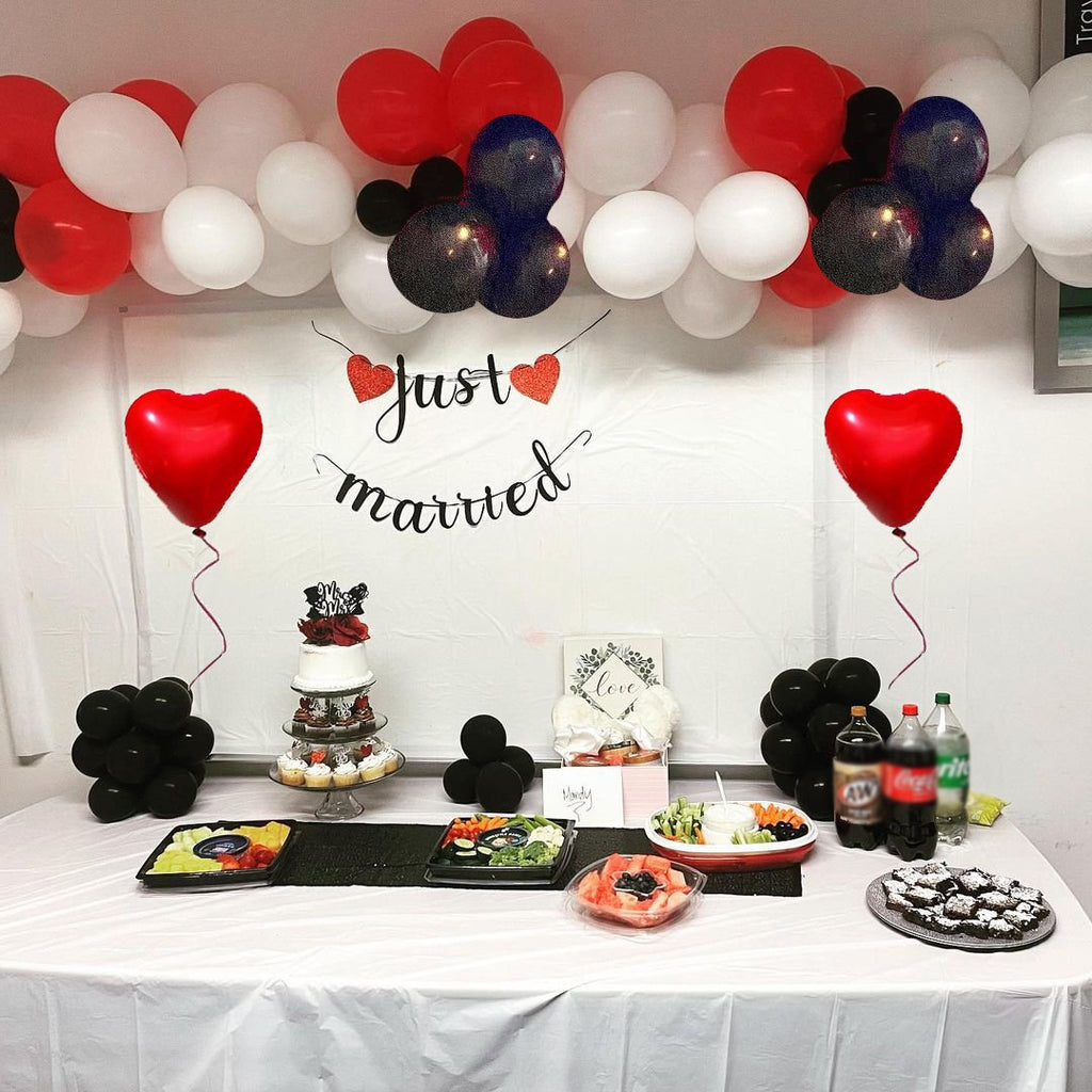 Wedding reception table with cake, cupcakes, fruit platters, snacks, drinks, and balloons.