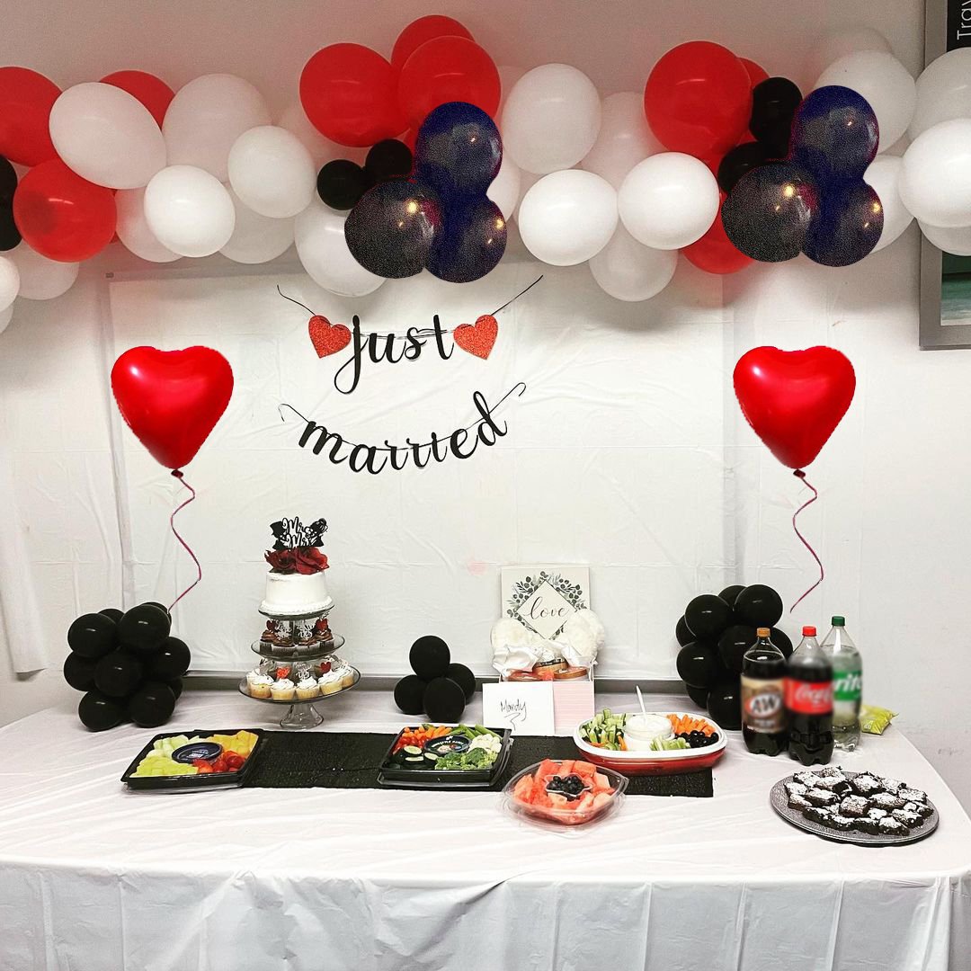 Wedding reception table with cake, cupcakes, fruit platters, snacks, drinks, and balloons.