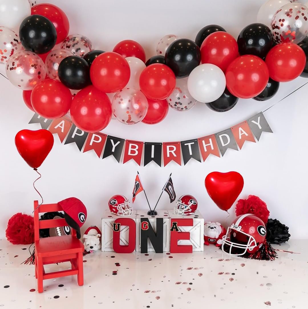 Birthday party setup with balloons, a banner, a red chair, football helmets, and large letters spelling 'ONE'.