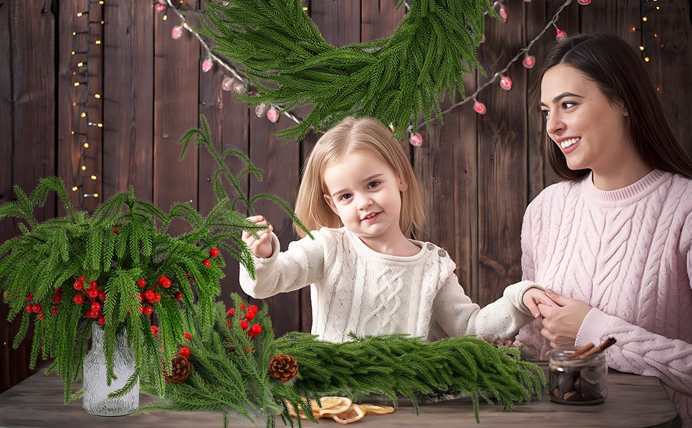 Mother and daughter crafting with artificial pine branches and red berries for Christmas decor