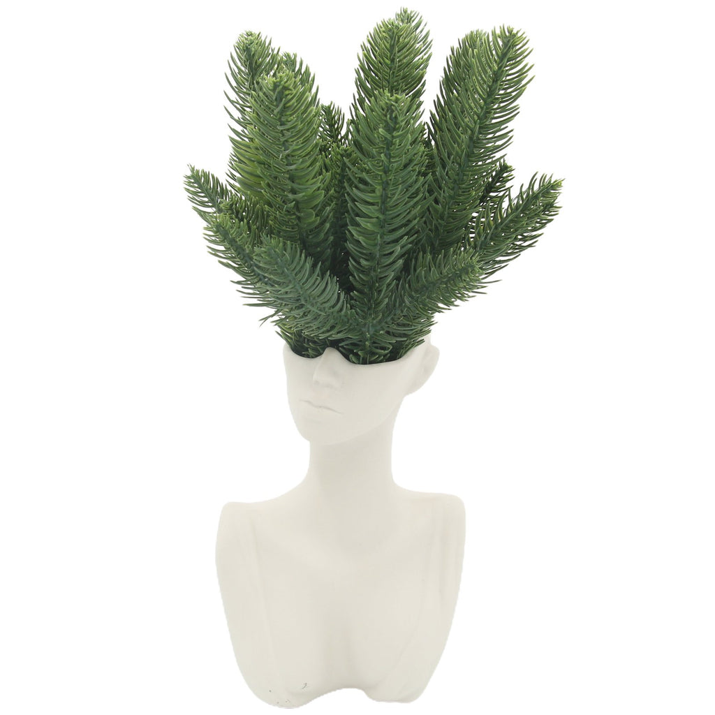 White bust vase with artificial green pine branches emerging from the top