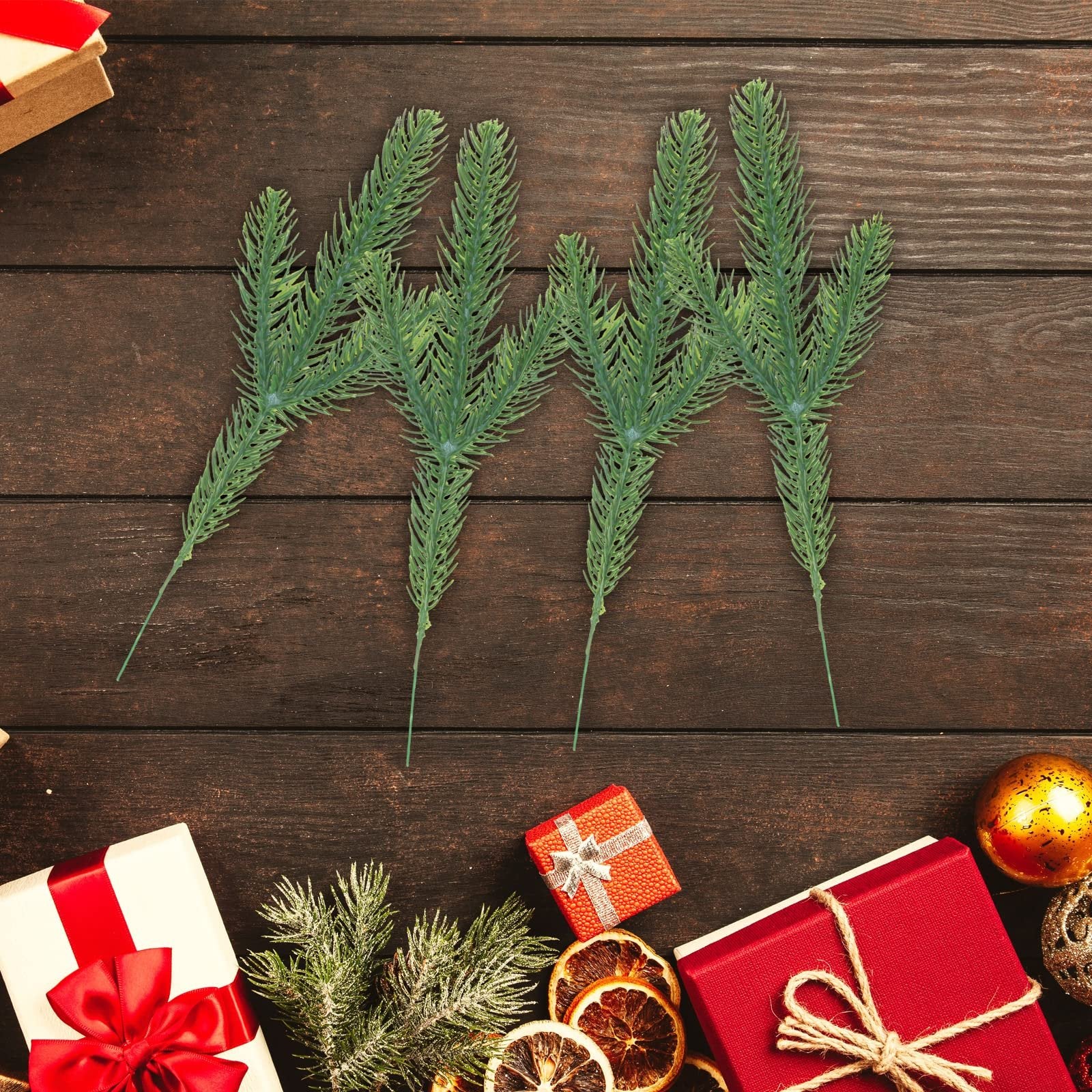 Artificial pine branches arranged on a wooden surface with Christmas decorations