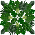 Assortment of artificial tropical leaves arranged in a circular pattern on a white background.