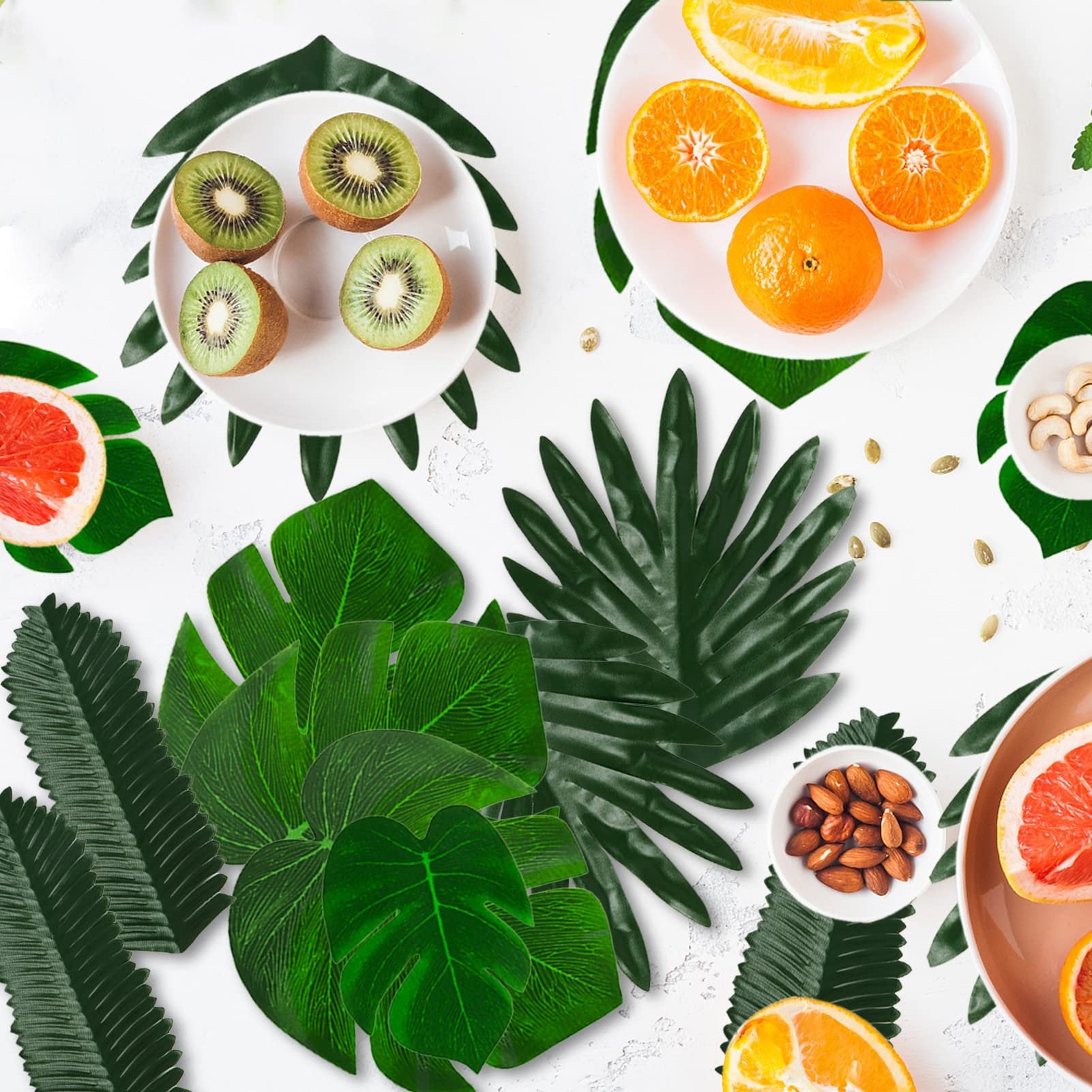 Assortment of tropical leaves with sliced fruits and nuts on a white background