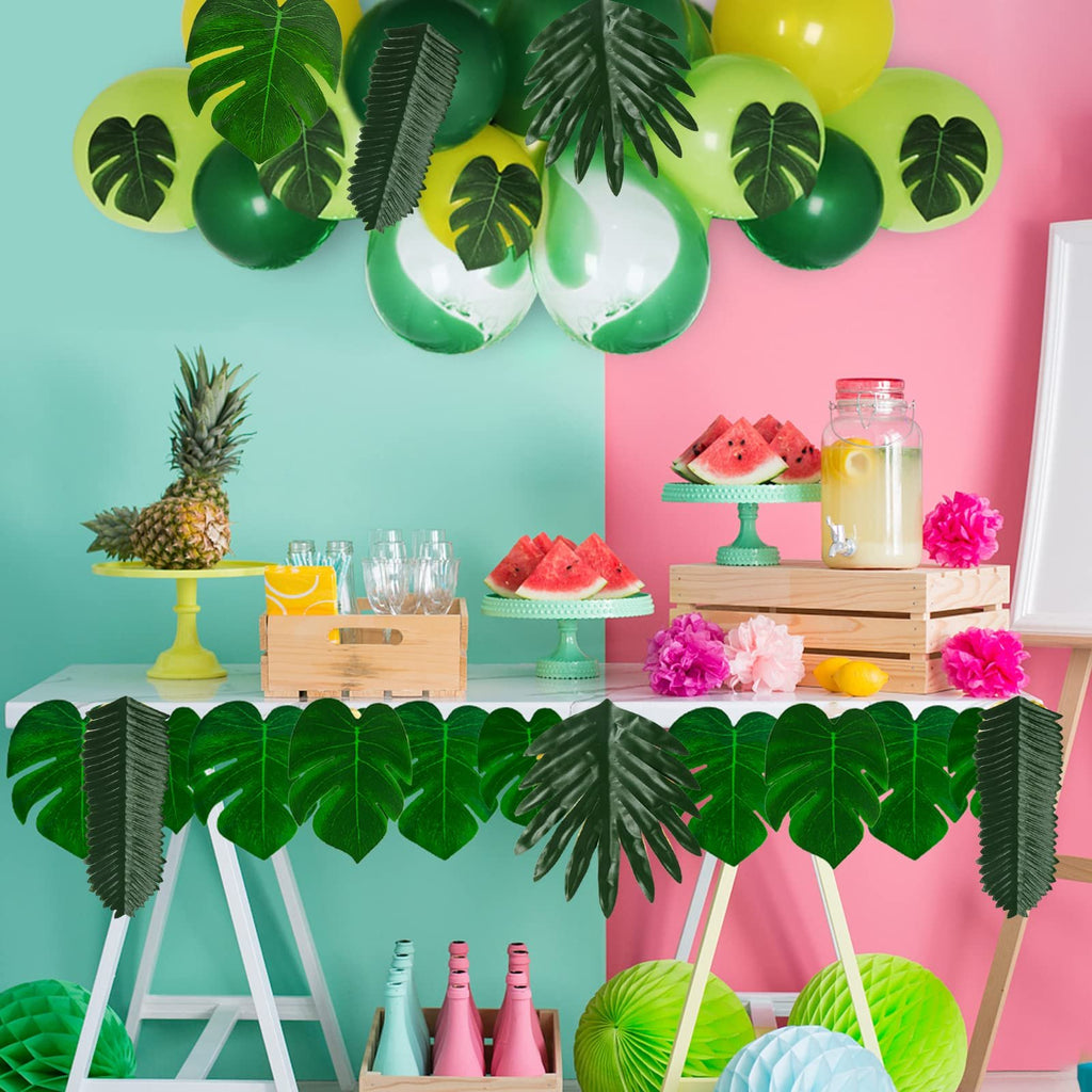 Tropical party setup with artificial leaves, balloons, pineapple, watermelon, and drinks