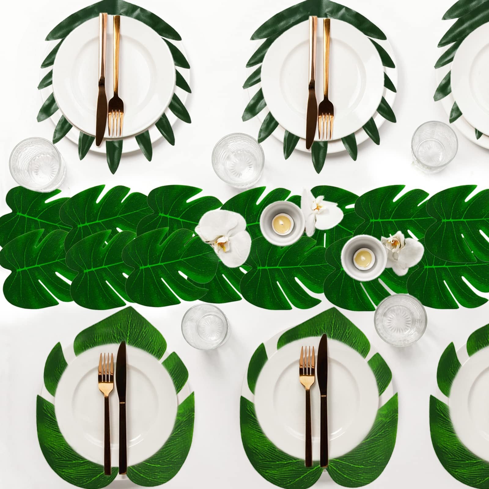 Table setting with artificial tropical leaves as placemats and a runner, white plates, gold cutlery, and glasses