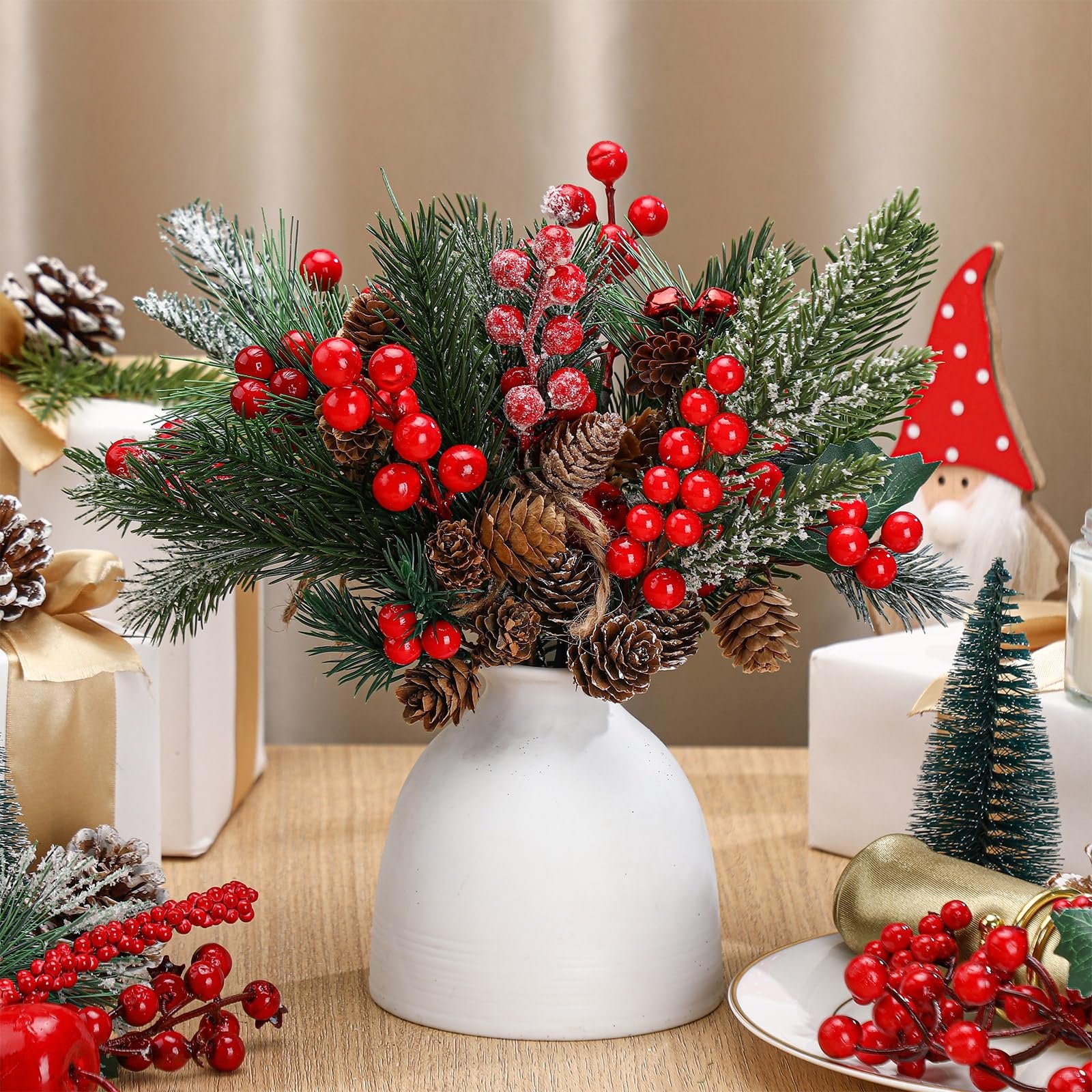 Christmas floral arrangement with pine needles, red berries, and pinecones in a white vase, surrounded by gifts and a gnome.