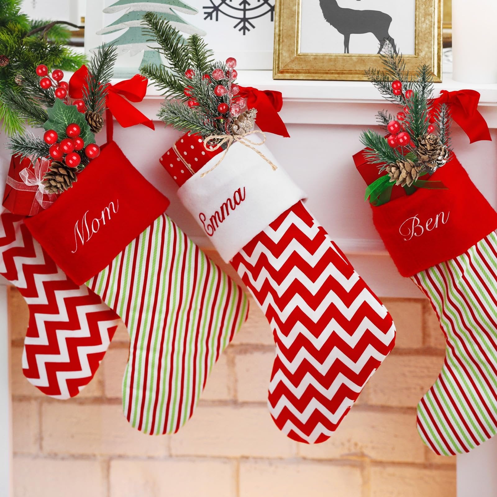 Three Christmas stockings decorated with faux pine sprigs, berries, and pinecones hanging on a mantelpiece.