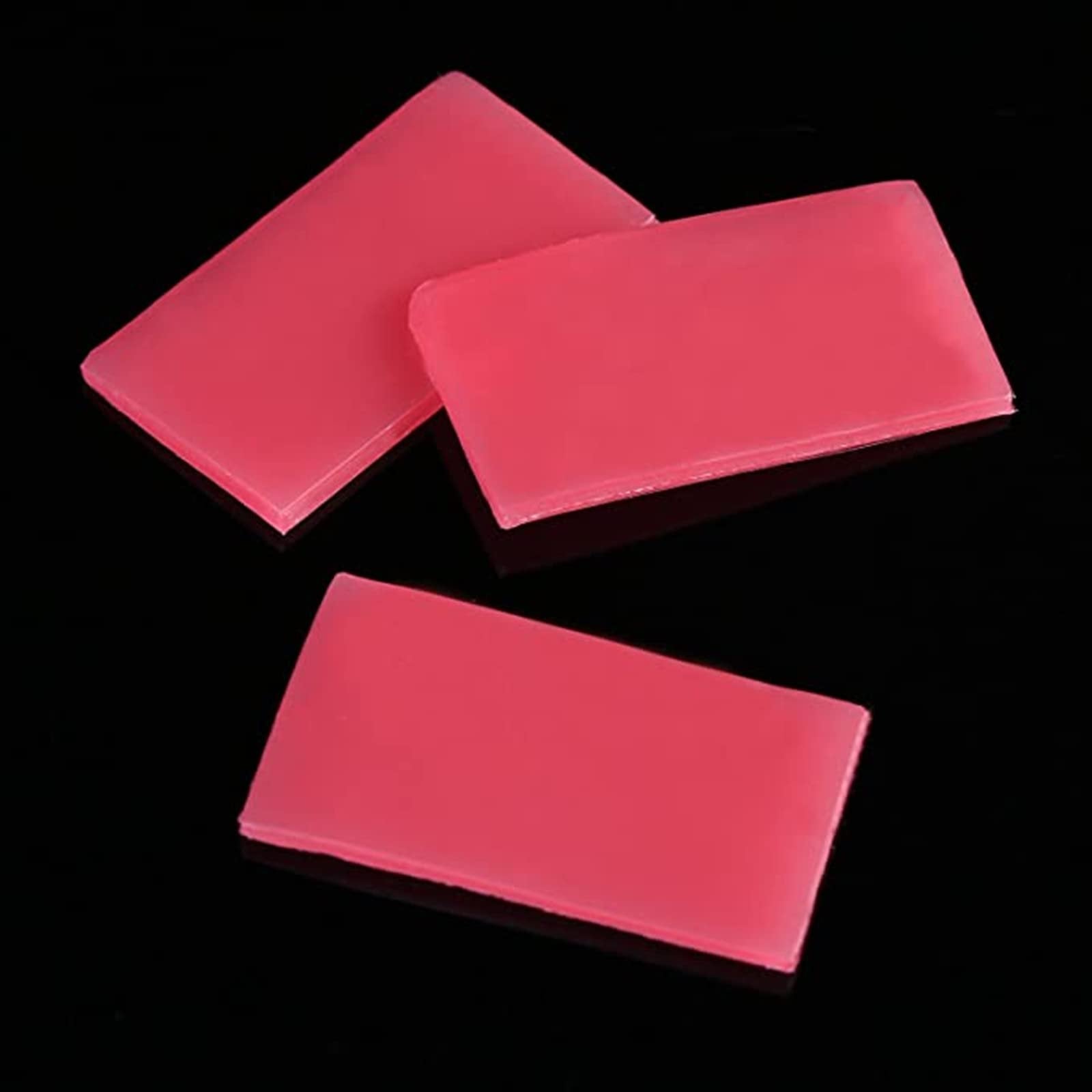 Three rectangular blocks of pink diamond painting wax clay on a black background.