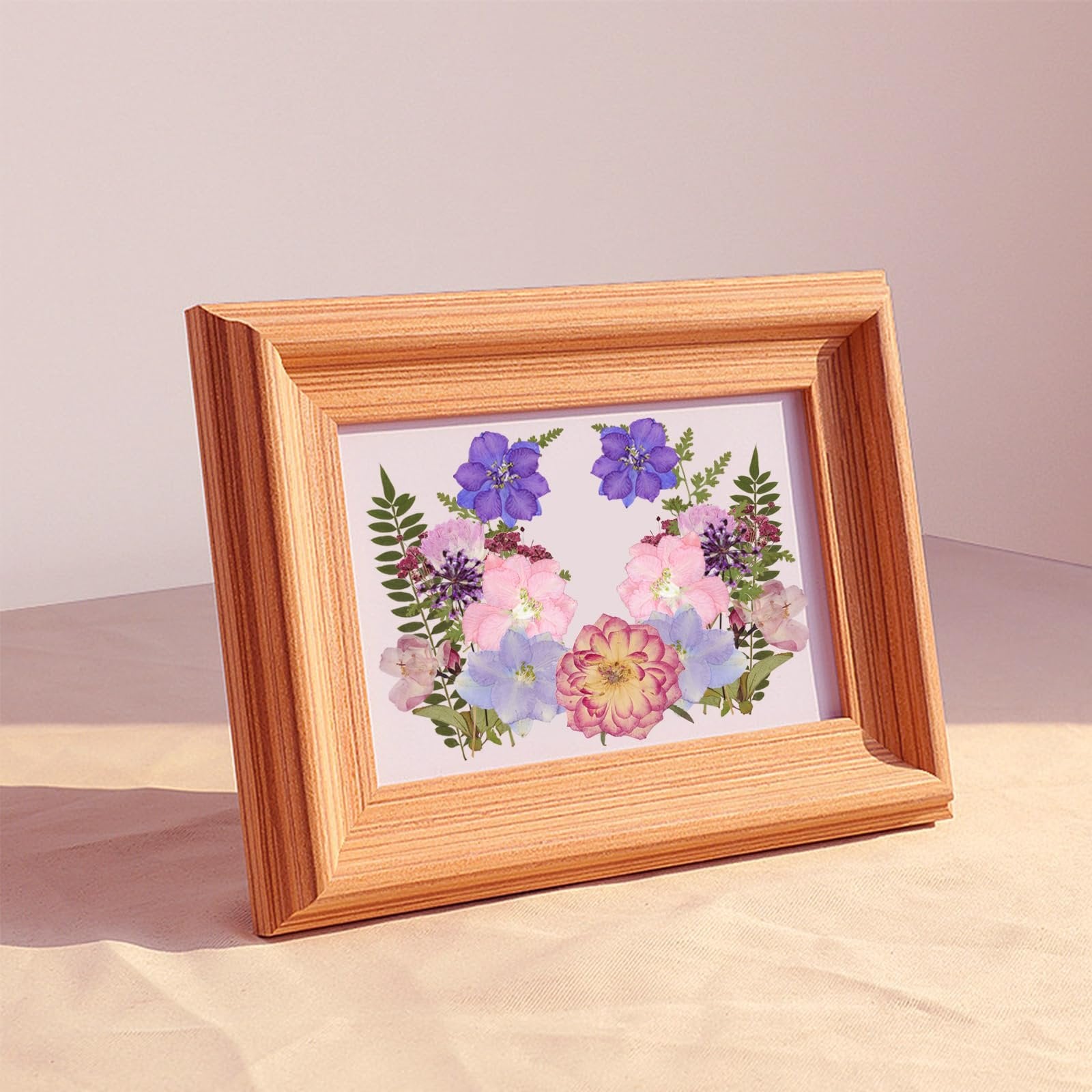 Wooden picture frame displaying a colorful arrangement of dried pressed flowers and leaves.