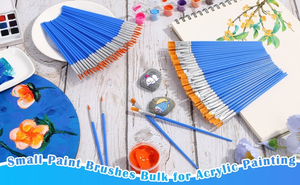 Two bundles of blue-handled paint brushes with orange bristles arranged on a wooden surface, surrounded by art supplies.