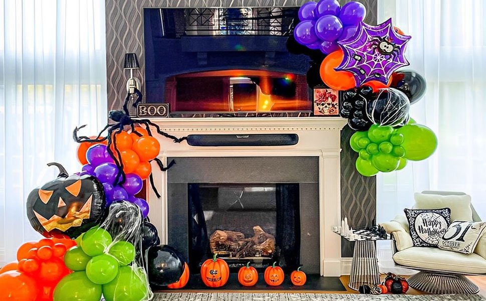 Halloween balloon arrangement with jack-o'-lantern, spiderweb, and assorted colored balloons decorating a fireplace.