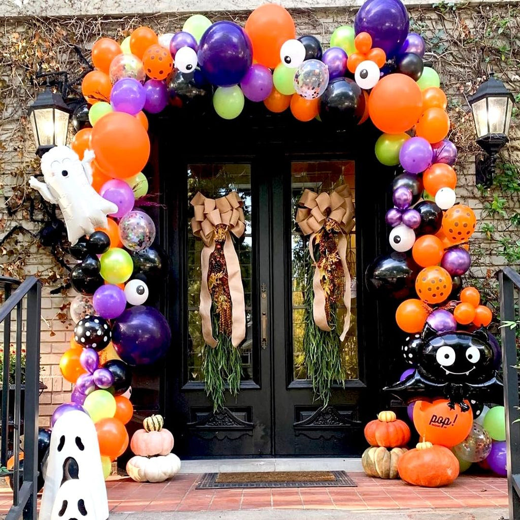 Halloween balloon arch and decorations in black, orange, purple, and green with ghost and bat balloons.