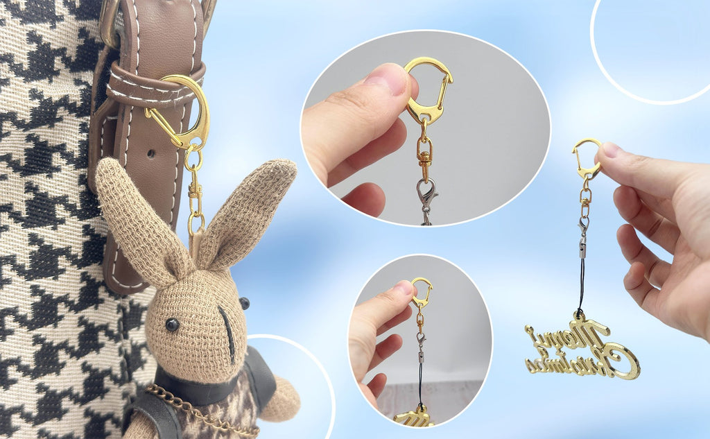 Gold metal lobster claw clasp keychain with a 'Merry Christmas' charm, shown attached to a bag and held by hand.